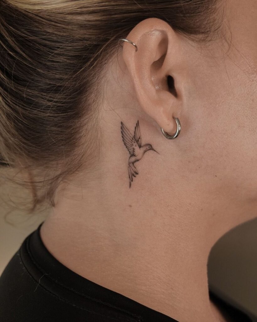 A behind-the-ear hummingbird tattoo