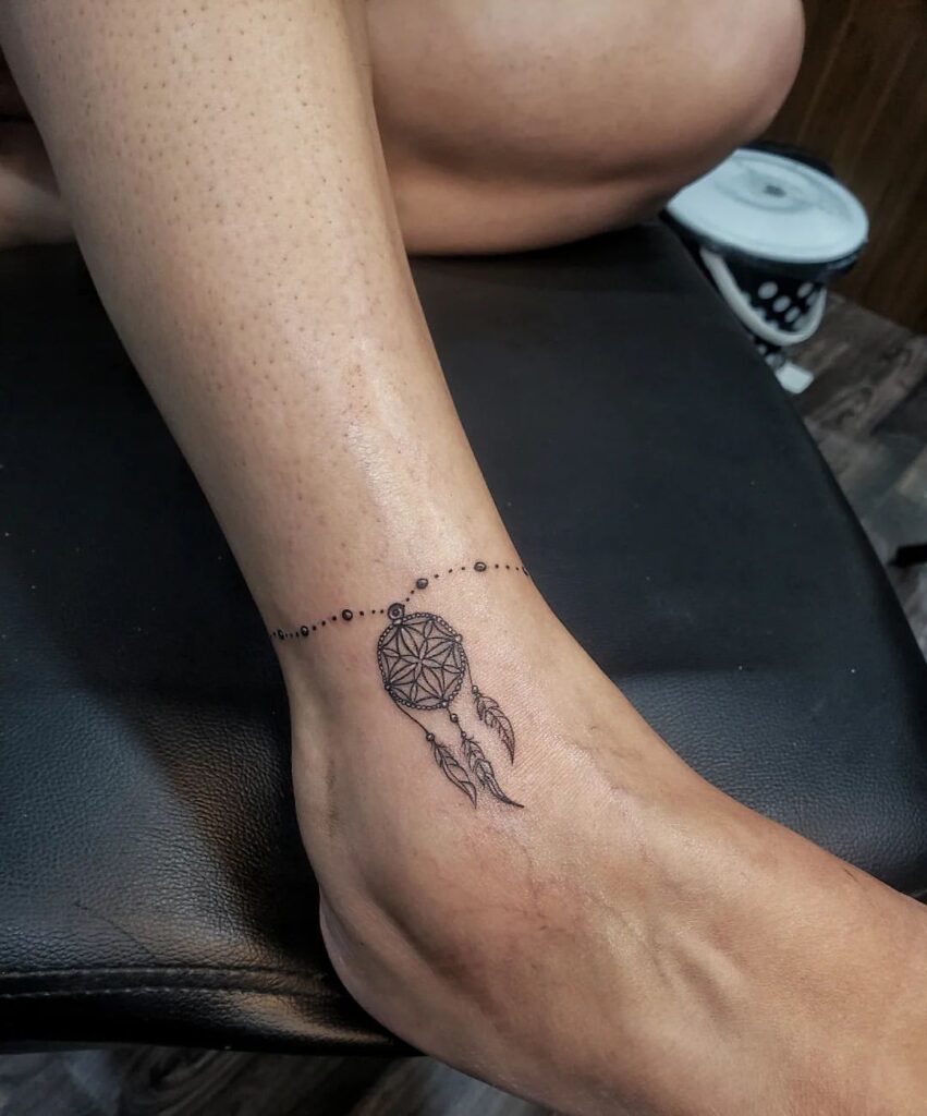 A black and gray dream catcher tattoo on the ankle