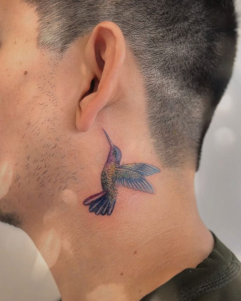 A colorful behind-the-ear hummingbird tattoo 