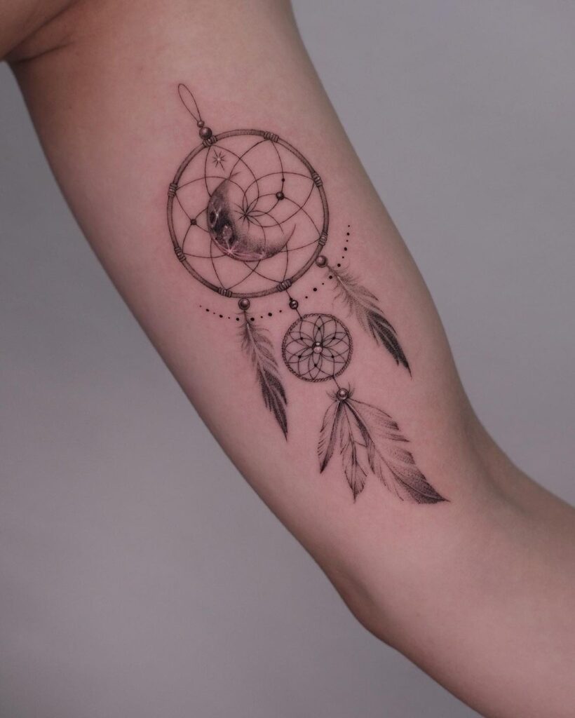 A fine-line dream catcher tattoo on the arm