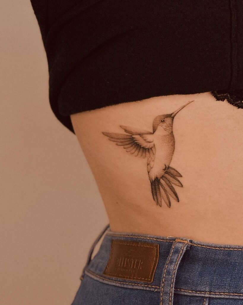 A hummingbird tattoo on the side of the stomach