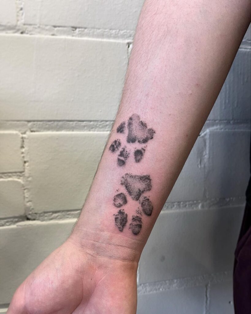 A tattoo of two paw prints on the wrist