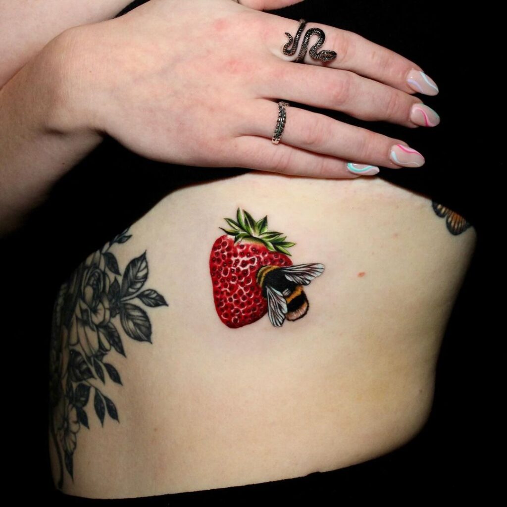 Bee and strawberry tattoo on stomach