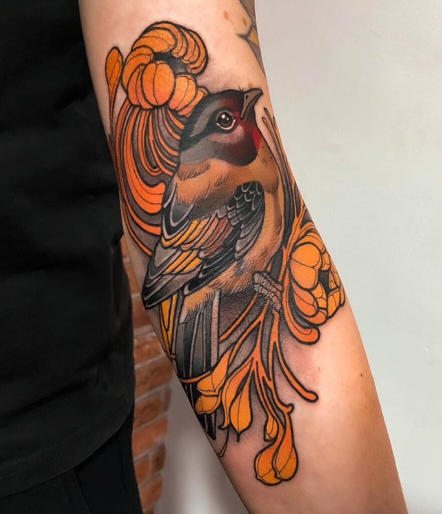 Neo-traditional tattoo of a bird with intricate feather details and autumn-hued flowers, showcasing a harmonious blend of naturalistic and stylized elements, inked on the arm for a bold and artistic expression.