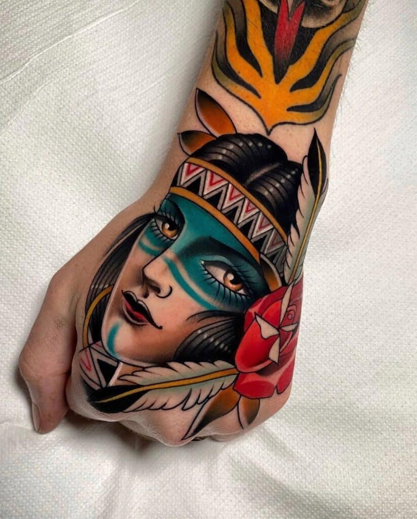 Neo-traditional tattoo on forearm featuring a portrait of a woman with cultural headgear and vibrant face paint, framed by a tiger motif and red floral accents, exemplifying the rich detail and color palette characteristic of neo-traditional tattoos.