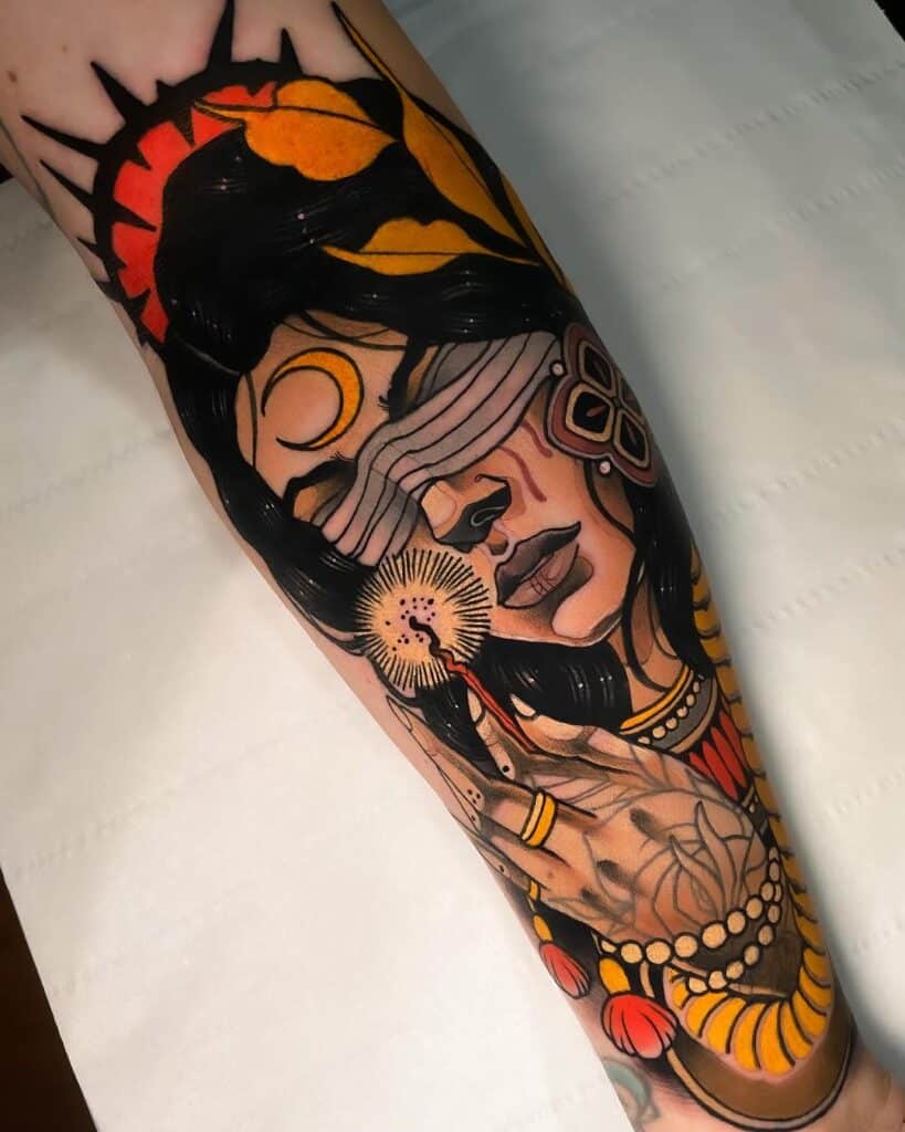 Neo-traditional tattoo on forearm featuring a detailed portrait of a woman with a blindfold, surrounded by sun rays and dandelion motifs, executed with bold lines and a warm color palette.